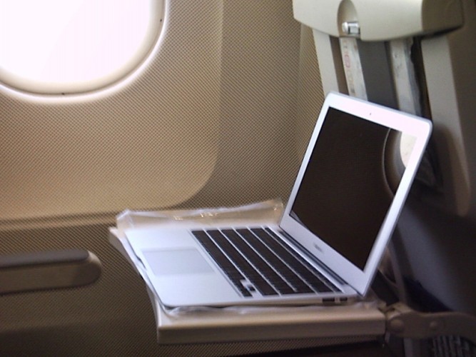 Sam's Macbook Air on the tray table in his window seat.