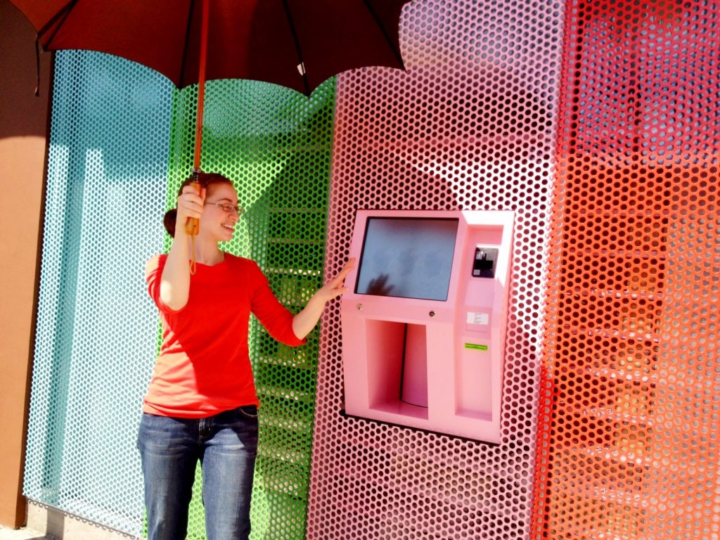 A parasol is required to keep the strong Spring sun off the screen at the Sprinkles cupcake vending machine in Beverly Hills . mobile Photography